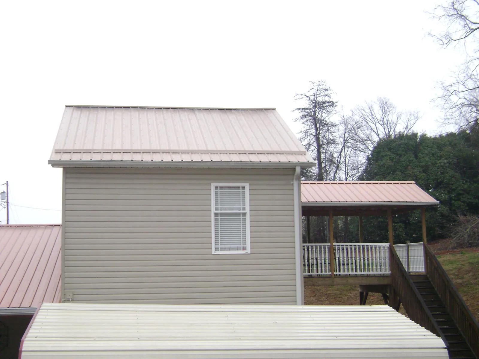 Tan metal roofs on a two story addition and attached porch, from a Roof Replacement job in Burbank